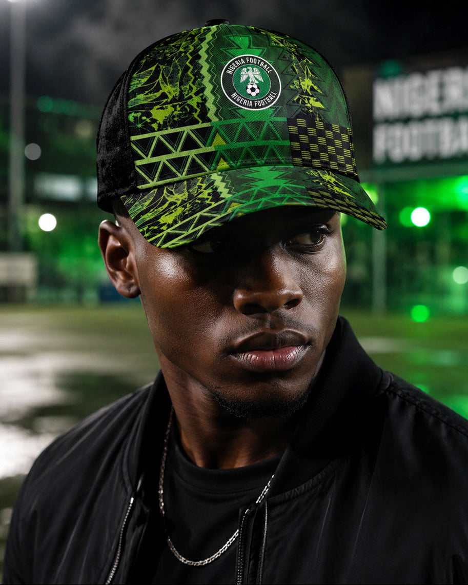 Person wearing a green and black cap with a logo on a sports field at night.